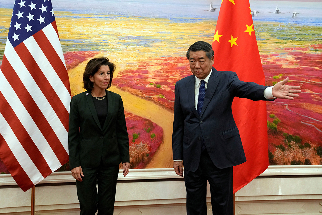 U.S. Commerce Secretary Gina Raimondo stands next to Chinese Vice Premier He Lifeng in front of their respective flags.