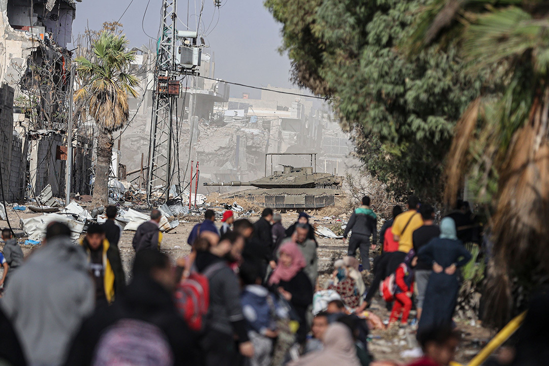 Palestinian families pass an Israeli tank as they flee Gaza City