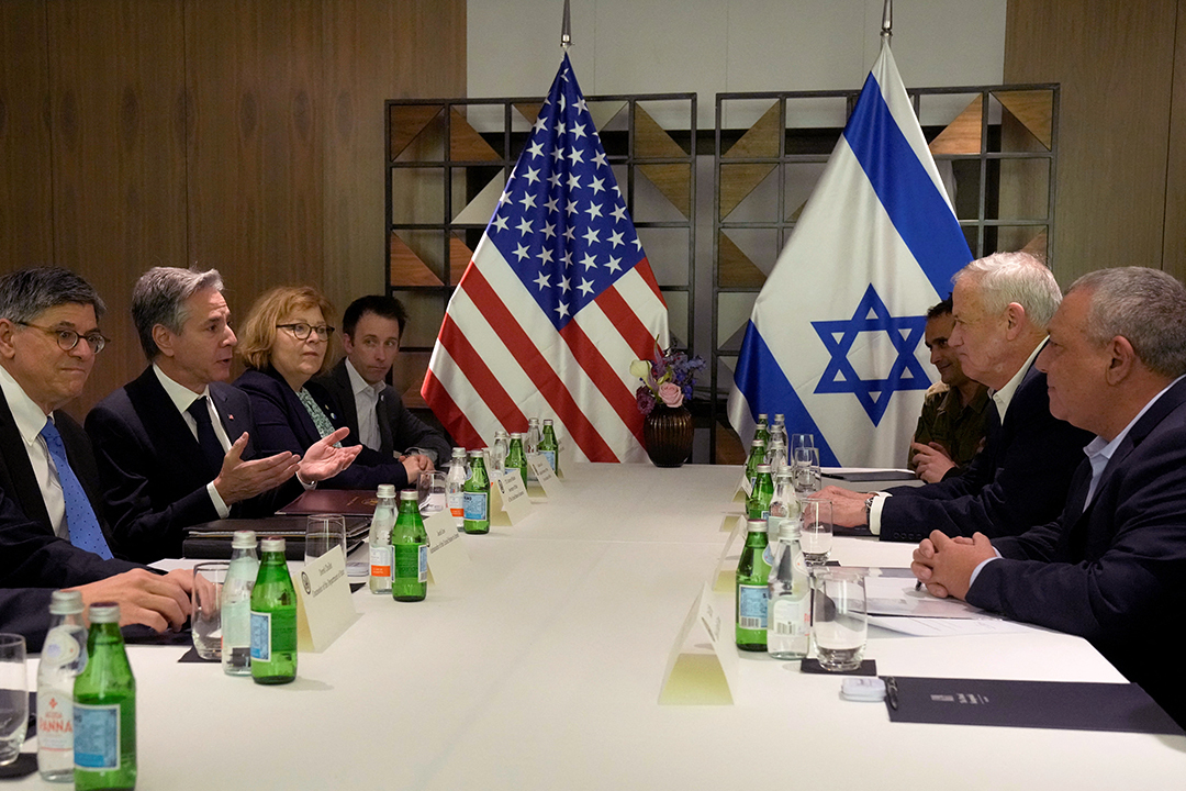 Leaders from the United States and Israel gather, seated across from one another at a table for negotiations with the flags of each country displayed at the table's end.
