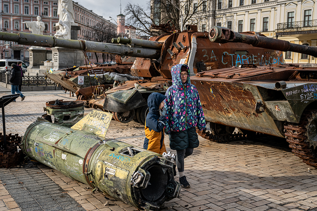 Ukrainian people walk along destroyed Russian vehicles in Kyiv.