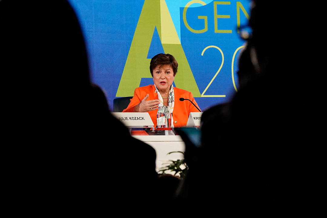 The shadows of two audience members foreground the head of the IMF speaking at a panel.