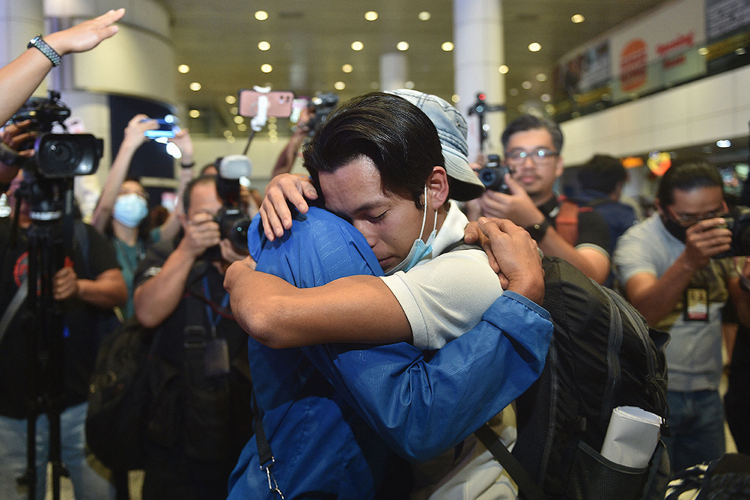 One of the group of six Malaysian men (R) rescued from a human trafficking syndicate in Myanmar is given a hug upon arrival at Kuala Lumpur International Airport in Sepang on December 21, 2022.