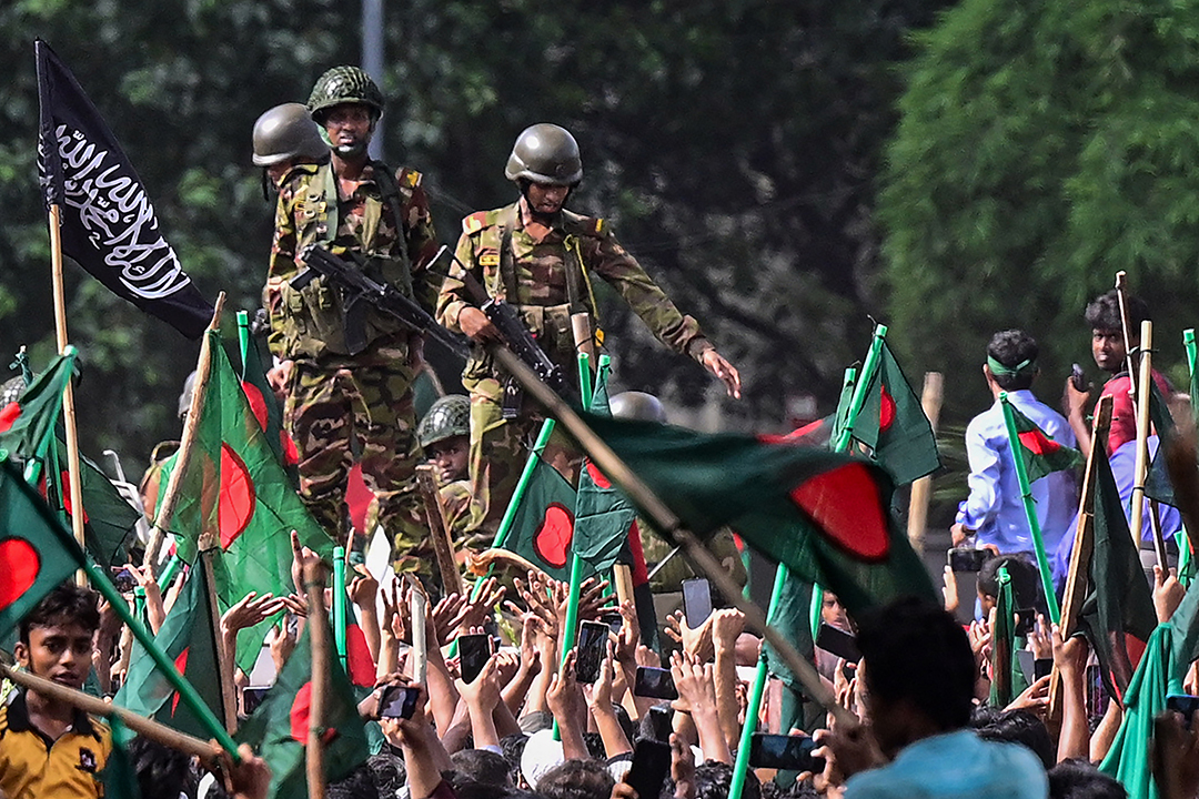 Anti-government protesters march toward former Prime Minister Sheikh Hasina’s palace as army personnel stand guard in Dhaka, Bangladesh, on August 5, 2024.