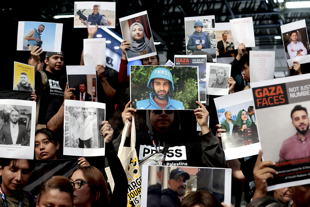 Mexican journalists and students hold up signs of journalists in protest. 
