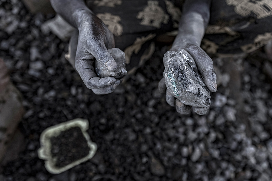 Two hands hold up a stone in each palm, with rocks in the background.