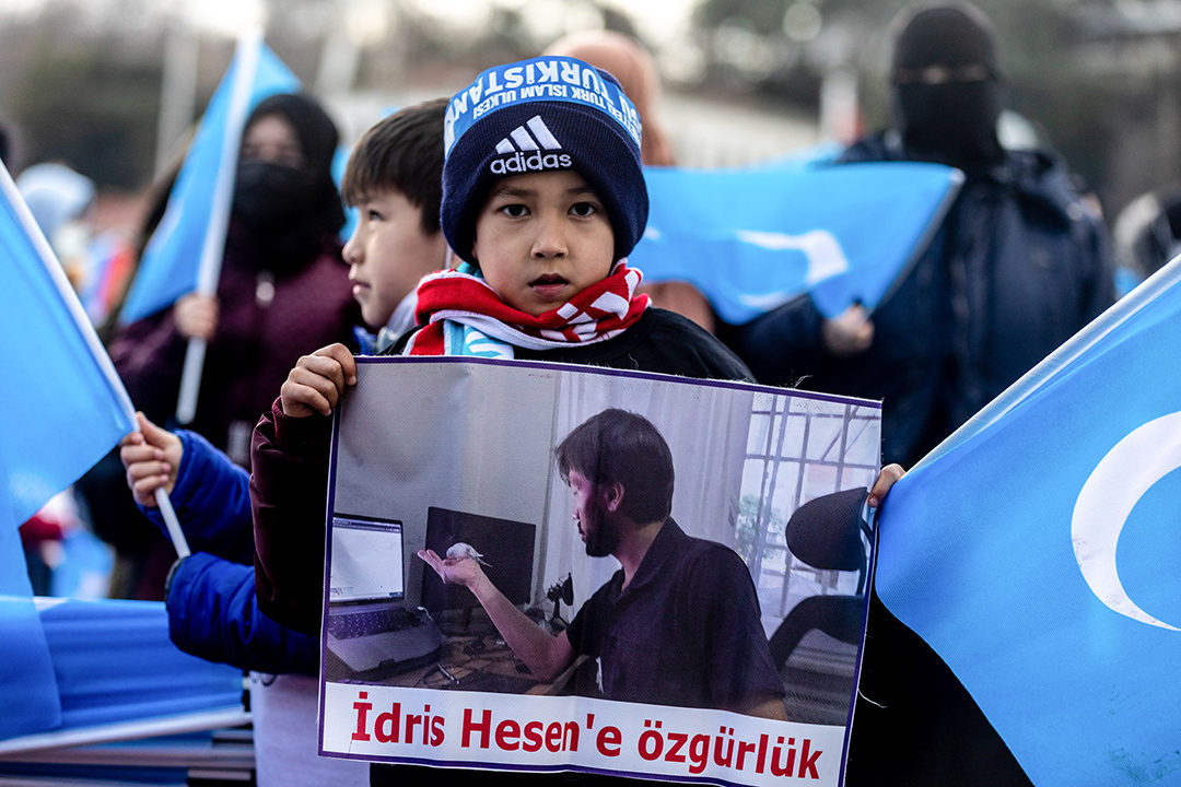 An image of a small boy in a blue coat holding a sign